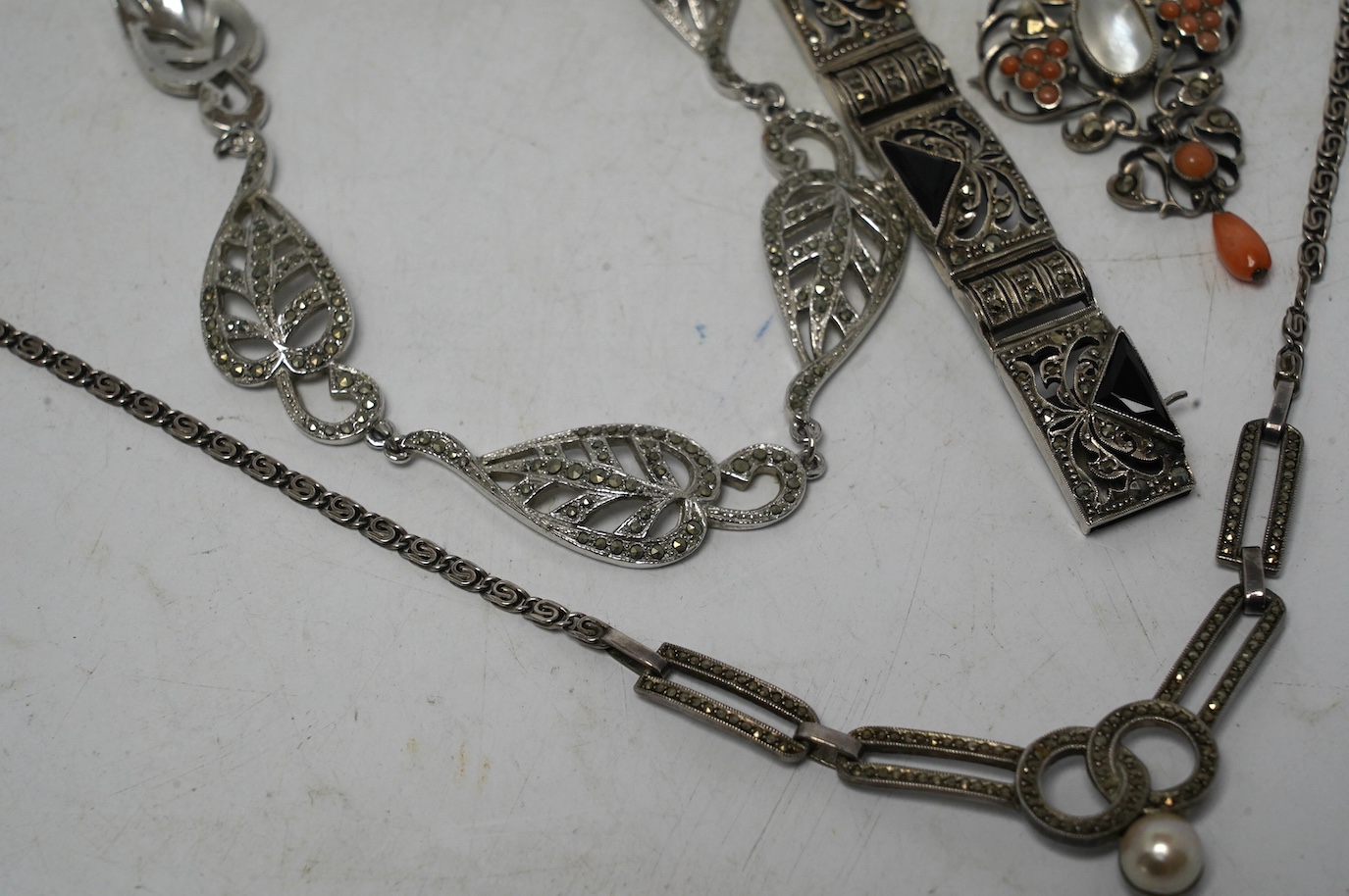 An early to mid 20th century white metal, mother of pearl and coral bead set drop pendant necklace, overall 60cm, together with two white metal and marcasite set necklaces, one stamped 925 and a German 935 marcasite and